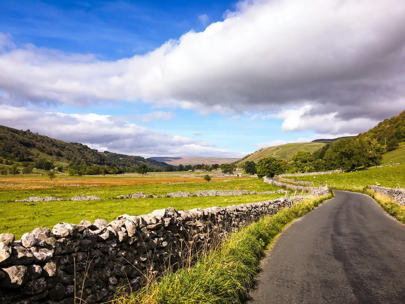 A single-track road running between drystone walls and green fields in North Yorkshire